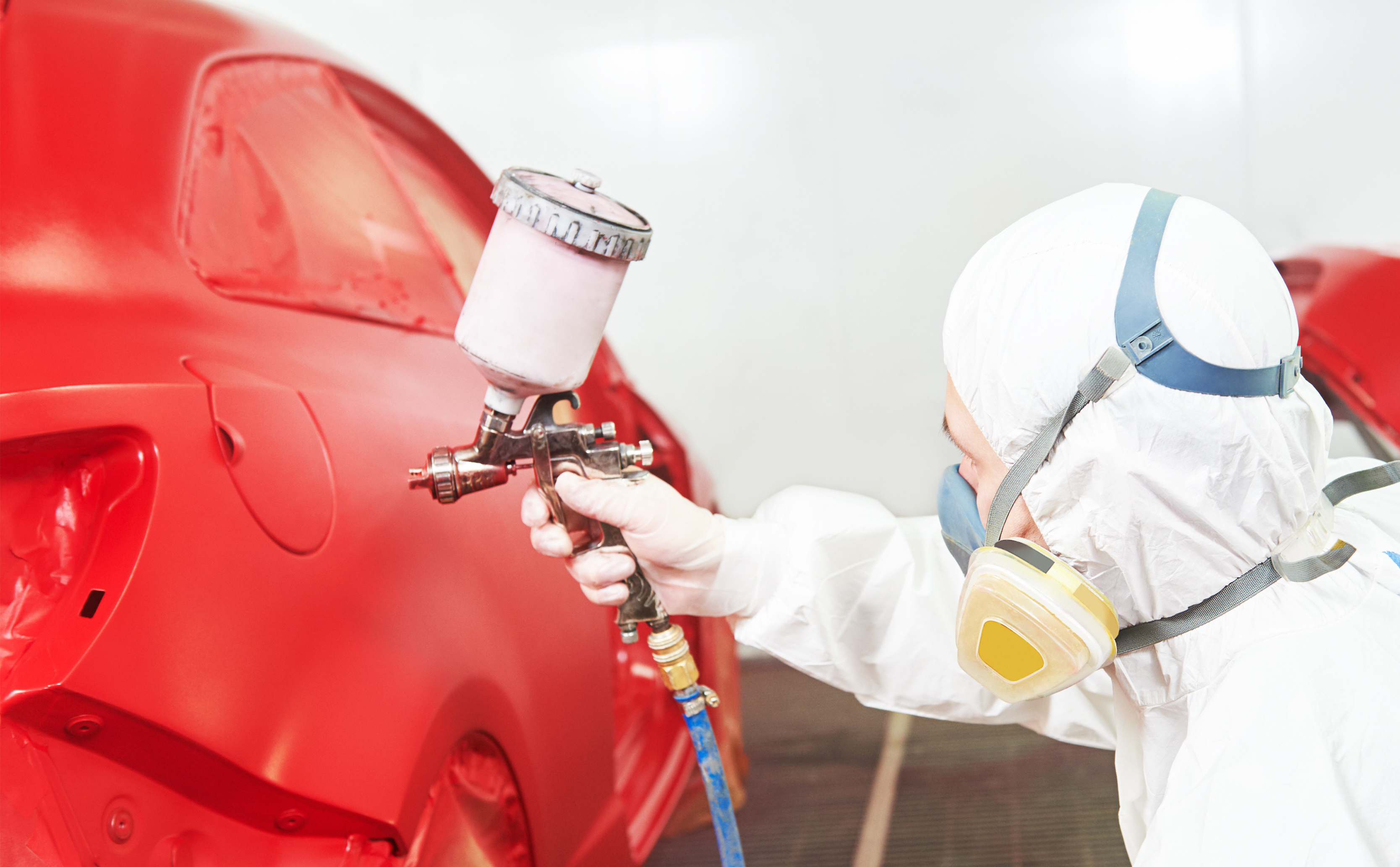 A man painting a car with water-based automotive paint